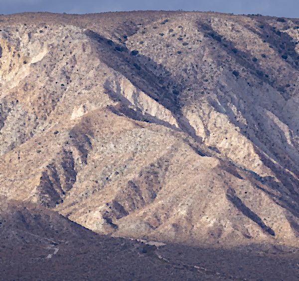 Bare desert mountains under a hard sky